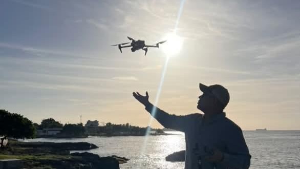 Kenny lanzando un DJI en la costa al atardecer — AeroVision Studio