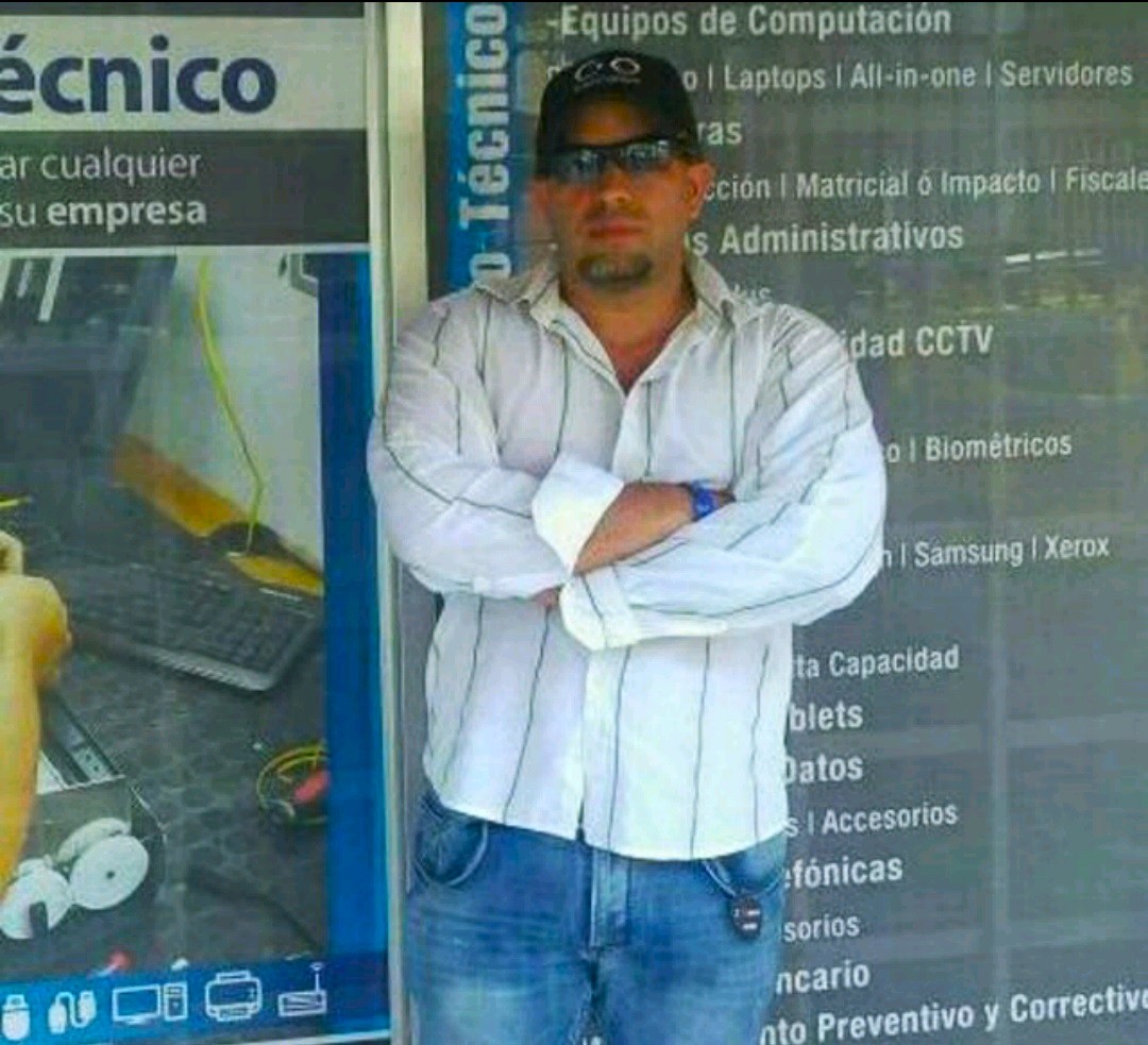 Kenny en KRA Computer — catálogo de servicios técnicos visible al fondo (Venezuela, era 1998-2013)